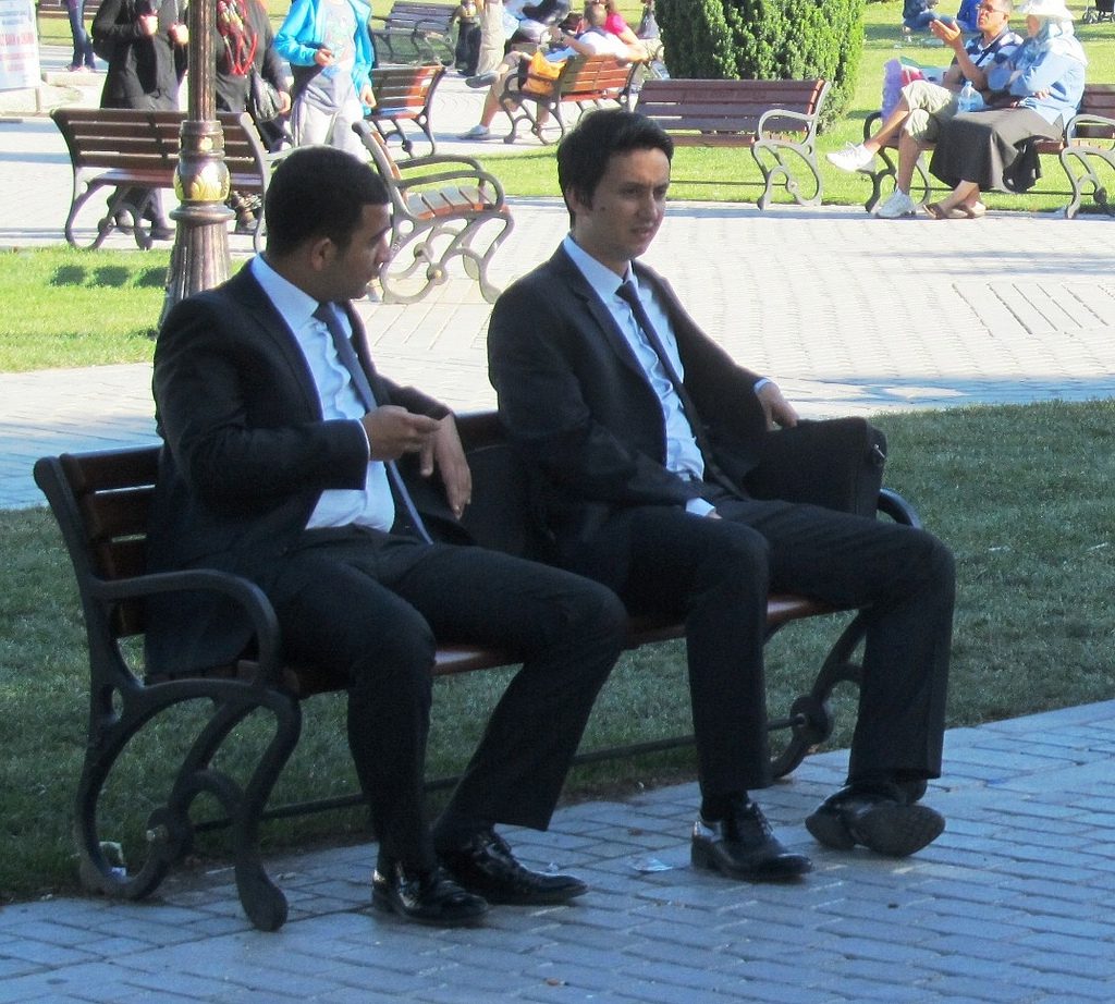 men in suits sitting on bench