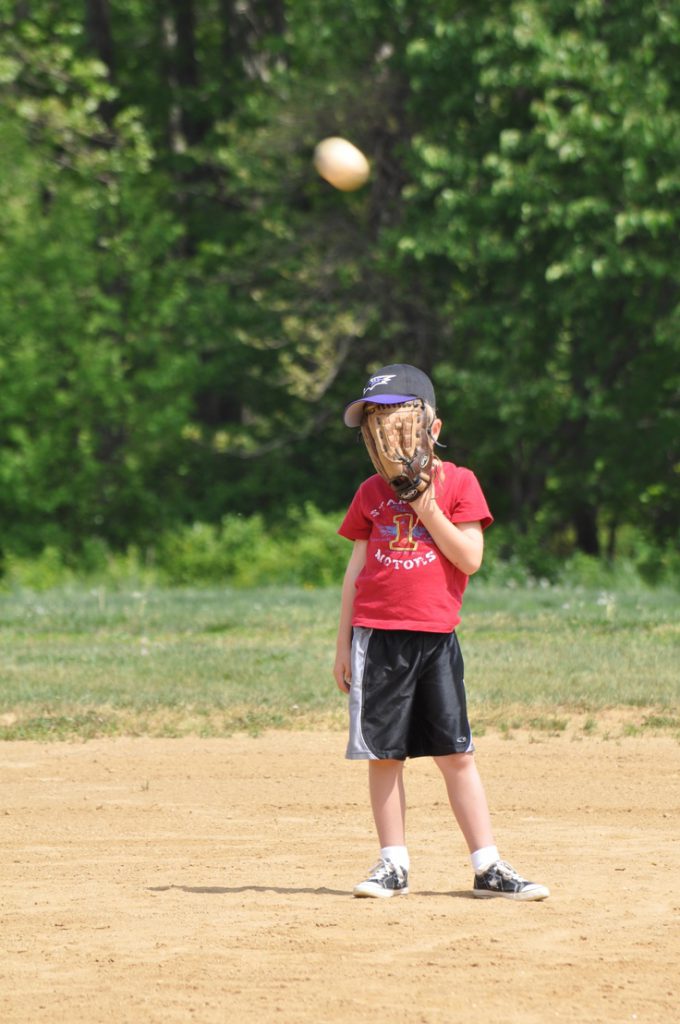 boy covering his face for a fly ball