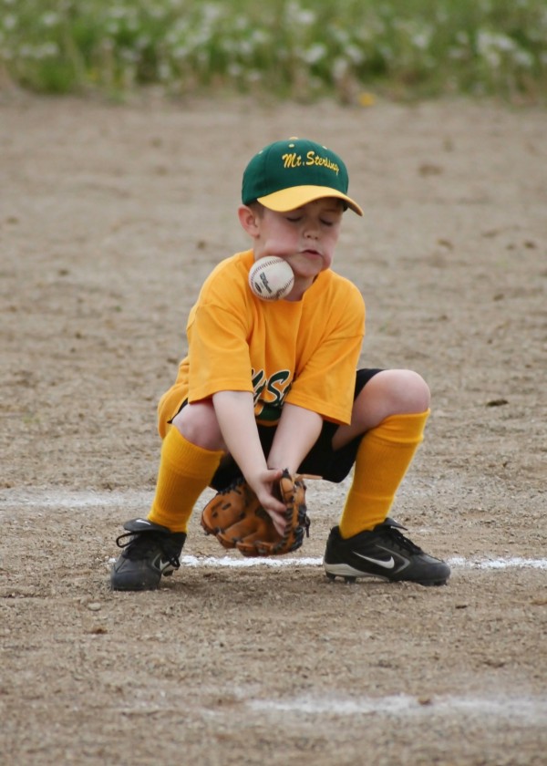 young player getting hit in face with grounder